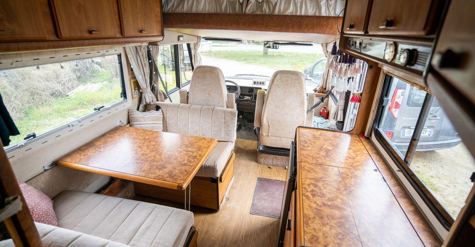 Interior of a classic camper van with wooden furniture and a compact living space.